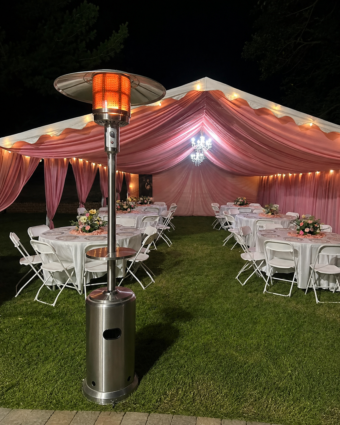Calentador exterior frente a una carpa rosa iluminada por Mariposa Services