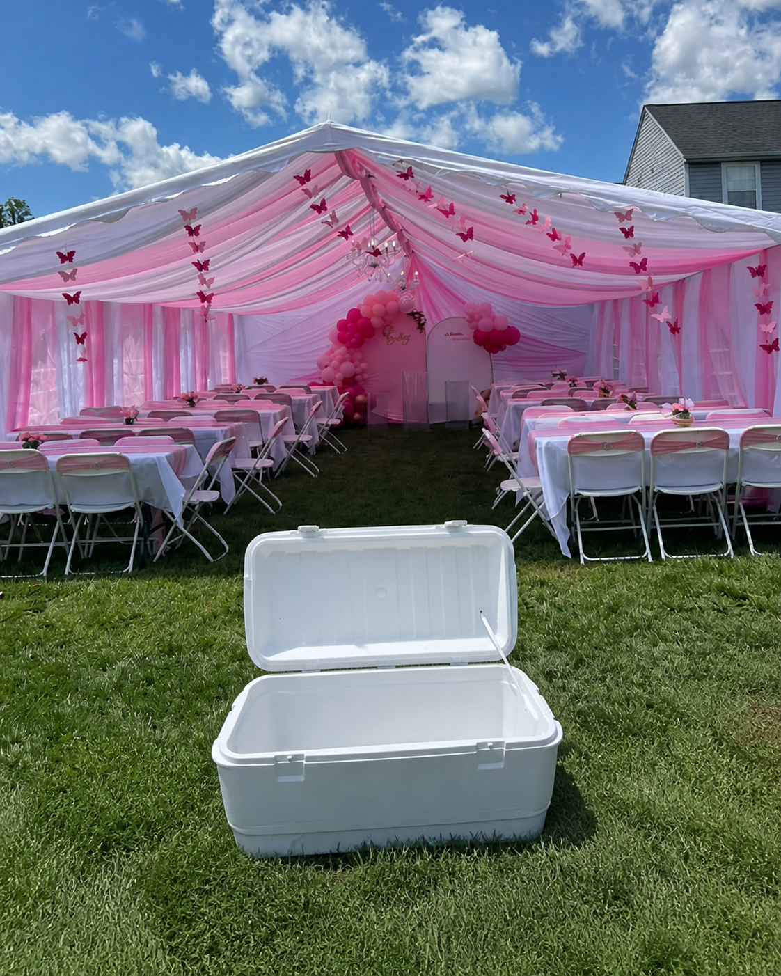 Hielera blanca frente a una carpa rosa decorada por Mariposa Services